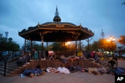FILE - Migrants sleep under a gazebo at a park in Reynosa, Mexico, March 27, 2021. The camp of migrants were mainly from Guatemala, El Salvador and Honduras.