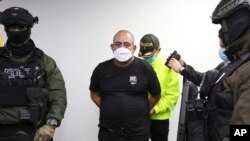 En esta foto proporcionada por la Oficina de Prensa de la Policía de Colombia, uno de los narcotraficantes más buscados del país, Dairo Antonio Usuga David, alias "Otoniel", es escoltado y esposado en Bogotá, Colombia, el 23 de octubre de 2021.