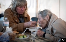 People have a meal after arriving from the Ukrainian city of Mariupol at a center for displaced people in Zaporizhzhia, Ukraine, May 3, 2022. (AP Photo/Evgeniy Maloletka)