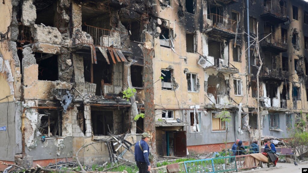 在乌克兰马里乌波尔一名男子从被炸成废墟的公寓楼前走过。（2022年5月4日）(photo:VOA)