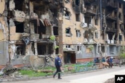 A man walks past a destroyed apartment building in Mariupol, Ukraine, May 4, 2022.