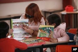 Teacher Elizabeth Mendoza and a student point at a lessons book at Casa Kolping. (AP Photo/Christian Chavez)