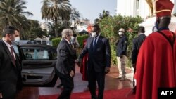 Senegal's President Macky Sall, center, greets United Nations Secretary-General Antonio Guterres, left, as Guterres arrives at the presidential palace during his West Africa tour, in Dakar, May 1, 2022.