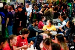 FILE - Customers, some wearing face masks, dine at the Reading Terminal Market in Philadelphia, April 22, 2022.