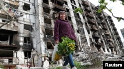 A local resident walks near an apartment building heavily damaged during Ukraine-Russia conflict in the southern port city of Mariupol, Ukraine on May 2, 2022.