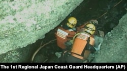FILE - Rescuers tend to a person found near Japan's Shiretoko Peninsula, April 24, 2022. On Monday, the coast guard searched a tour boat operator's office as they looked into whether negligence caused the sinking. Credit: The 1st Regional Japan Coast Guard Headquarters via AP.
