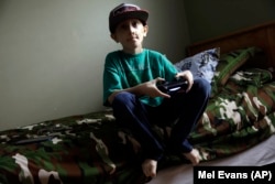 Mikey Richert,10, bermain video game di rumahnya. Ia didiagnosis menderita tumor otak pada usia 9 tahun. (Foto: AP)