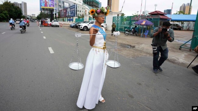 Cambodian-American lawyer Theary Seng, dressed in a pageant costume that reads "Lady Justice", walks outside Phnom Penh Municipal Court in Phnom Penh, Cambodia, Tuesday, May 3, 2022. Tuesday is the the final day of hearings for her trial on treason and a related charge for which she could receive a prison sentence of up to 12 years. (AP Photo/Heng Sinith)