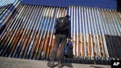 FILE - A migrant waits on the Mexican side of the border after U.S. Customs and Border Protection officers detained a couple of migrants crossing the U.S.-Mexico border on the beach, in Tijuana, Mexico, Jan. 26, 2022.