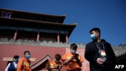 人們在北京紫禁城旁的一個新冠病毒核酸檢測點旁排隊等候進行檢測。 （2022年5月1日）