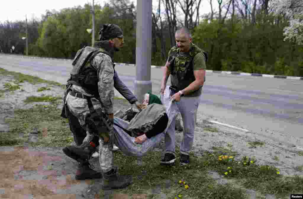 Volunteers carry an elderly woman as they evacuate residents from a village retaken by Ukrainian forces, next to a frontline in Kharkiv, Ukraine.