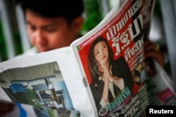 A man reads newspapers with a cover photo of Yingluck Shinawatra, sister of ousted premier Thaksin Shinawatra, in central Bangkok July 4, 2011.