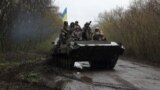 资料照：乌克兰军人站在装甲车上冲向前线。（2022年4月18日）
