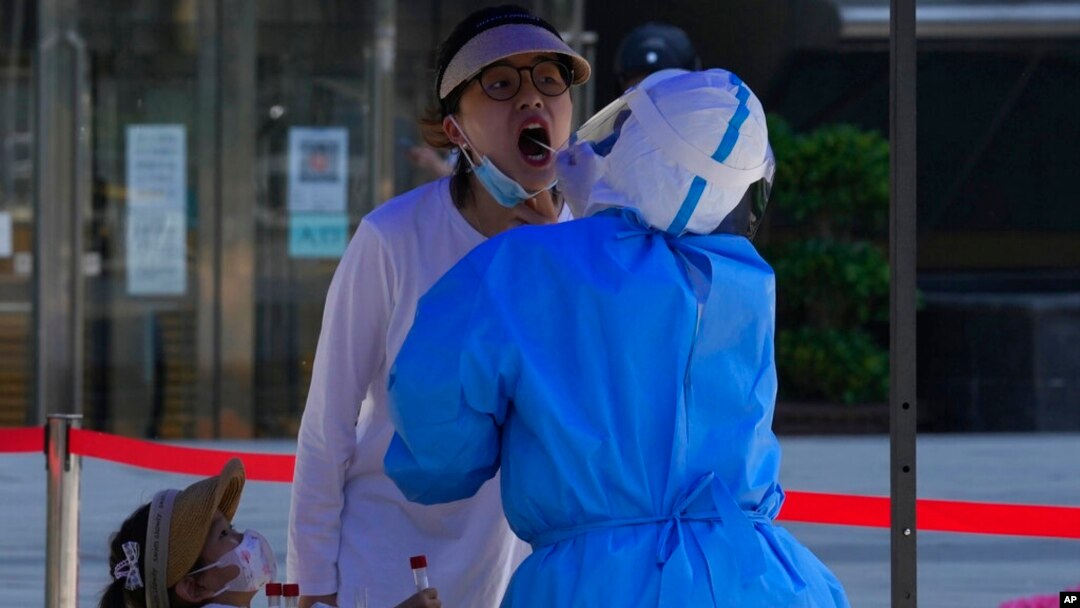A woman opens her mouth for a swab sample during mass COVID-19 testing, in Beijing, May 3, 2022.