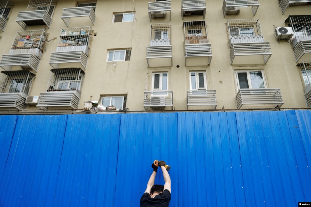 工人在北京市一个居民小区楼外竖起屏障进行封闭。（2022年4月29日）(photo:VOA)