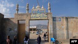 FILE - This picture taken on November 7, 2021 shows a student walking through the entrance of the Darul Uloom Hakimia madrassa where the Taliban Supreme Leader Hibatullah Akhundzada reportedly appeared, in Kandahar province.