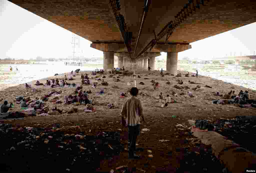 People sleep on the Yamuna river bed under a bridge on a hot summer day in New Delhi, India.
