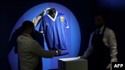 In this file photo taken in London on April 20, 2022 Sotheby's technicians adjust a shirt worn by Argentina's Diego Maradona during the 1986 World Cup quarterfinal match against England.