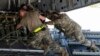 Airmen push over 8,000 pounds of 155 mm shells on to a C-17 cargo aircraft for transport, ultimately bound for Ukraine, April 29, 2022, at Dover Air Force Base, Del. 
