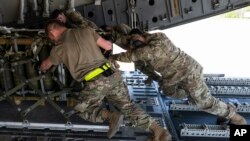 Airmen push over 8,000 pounds of 155 mm shells on to a C-17 cargo aircraft for transport, ultimately bound for Ukraine, April 29, 2022, at Dover Air Force Base, Del. 