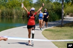 FILE - Jacky Hunt-Broersma finishes her 102nd marathon in 102 days, this one at Veterans Oasis Park, in Chandler, Arizona, April 28, 2022. (AP Photo/Ross D. Franklin)