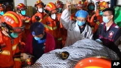 Para petugas penyelamat membawa orang kesembilan yang selamat dari insiden ambruknya gedung di Changsha, China. Orang tersebut ditemukan 88 jam setelah insiden terjadi, pada 3 Mei 2022. (Foto: Xinhua via AP/Chen Zeguo)