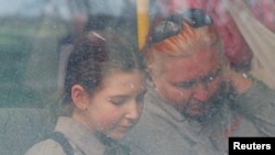 People are seen through a bus window as civilians from Mariupol, including evacuees from Azovstal steel plant, travel in a convoy to Zaporizhzhia, during Ukraine-Russia conflict in the Donetsk Region, Ukraine, May 2, 2022. 