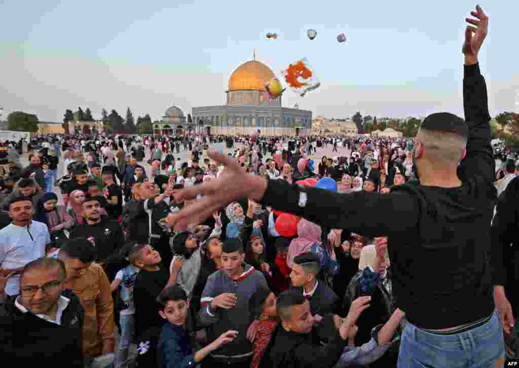 Seorang pria Muslim membagikan permen di depan masjid Kubah Batu usai salat Idulfitri, yang menandai akhir bulan suci Ramadhan, di kompleks masjid Al-Aqsa di Kota Tua Yerusalem, Senin 2 Mei 2022. (Foto: AFP)