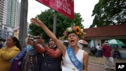 Cambodian-American lawyer Theary Seng, dressed in a pageant costume that reads "Lady Justice", shouts slogans outside Phnom Penh Municipal Court in Phnom Penh, Cambodia, Tuesday, May 3, 2022. 