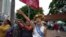 Cambodian-American lawyer Theary Seng, dressed in a pageant costume that reads "Lady Justice", shouts slogans outside Phnom Penh Municipal Court in Phnom Penh, Cambodia, Tuesday, May 3, 2022. 
