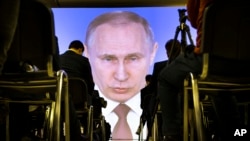 FILE - Journalists watch as Russian President Vladimir Putin gives his annual state of the nation address in Manezh in Moscow, Russia, March 1, 2018. 