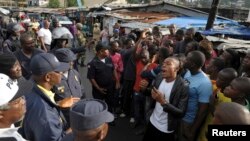 Members of Liberian security forces talk with a protester in the West Point neighbourhood in Monrovia Aug. 20, 2014.