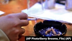 FILE - A person holds a cigarette in Durham, N.C., Dec. 17, 2009.