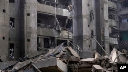 Seorang pria meneriakkan slogan-slogan menentang Israel saat berdiri di balkon apartemennya yang rusak di lokasi serangan udara Israel di Dahiyeh, Beirut, Lebanon, 1 November 2024. (Foto: AP)