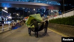 Para pemrotes pro-demokrasi Hong Kong memindahkan tendanya dari jalanan di luar kantor pusat pemerintah di Admiralty, Hong Kong (8/12).