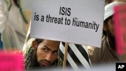 FILE - An Indian Muslim man holds a banner during a protest against IS, an Islamic State group, and the Paris attacks, in New Delhi, India, Nov. 18, 2015.