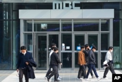 Orang-orang berjalan di depan kantor pusat penyiaran publik MBC di Seoul, Korea Selatan, Kamis, 10 November 2022. (Foto: AP)