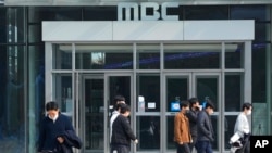 People walk by the headquarters of public broadcaster MBC in Seoul, South Korea, Thursday, Nov. 10, 2022.