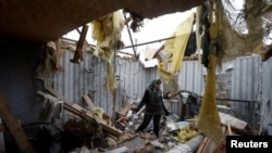 A woman removes debris inside a house destroyed during a Russian military attack in the village of Novooleksandrivka, in Kherson region, Ukraine Nov. 9, 2022.