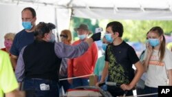 Silver Dollar City employee takes the temperature of guests before they are allowed to enter the park on just west of Branson, Mo. (Nathan Papes/The Springfield News-Leader via AP, File)