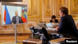 FILE - French President Emmanuel Macron talks with Russian President Vladimir Putin during a video conference at the Elysee Palace in Paris, France, June 26, 2020.