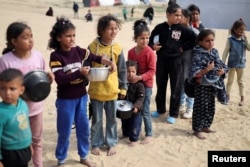 FILE — Displaced Palestinian children wait to receive free food at a tent camp, amid food shortages, in Rafah in the southern Gaza Strip, February 27, 2024.