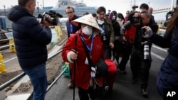 Seorang penumpang (mengenakan masker) dikerumuni oleh awak media saat turun dari kapal pesiar Diamond Princess di pelabuhan Yokohama, Jepang (foto: ilustrasi). 