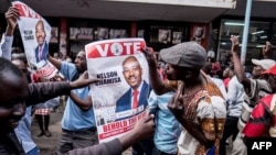 Supporters of Zimbabwean opposition MDC Alliance party leader Nelson Chamisa hold his campaign posters as they gather outside the MDC Alliance's headquarters in Harare on July 31, 2018.