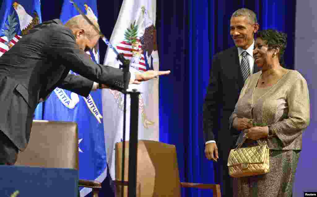 Presidente Barack Obama caminha com Aretha Franklin e o Procurador Geral Eric Holder faz a vénia a Aretha, depois de revelado o retrato de Holder no Departamento de Justiça, Washington DC, 27 de Fevereiro, 2015.