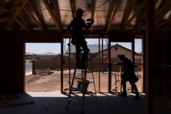 Electricians install wires at a newly constructed home, Aug. 19, 2021, in Somerton, Ariz.