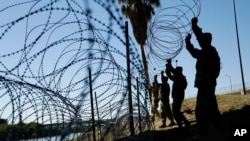 Members of the U.S. military install multiple tiers of concertina wire along the banks of the Rio Grande near the Juarez-Lincoln Bridge at the U.S.-Mexico border, Nov. 16, 2018, in Laredo, Texas.