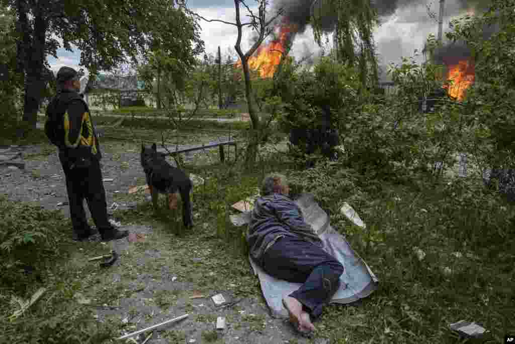 Un hombre yace en el suelo mientras observa su casa en llamas destruida por un ataque aéreo ruso en Vovchansk, Ucrania, el 11 de mayo de 2024. (Foto AP/Evgeniy Maloletka)