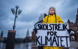 FILE - Activist Greta Thunberg holds a placard reading "School strike for the climate" during a demonstration against climate change outside the Swedish parliament in Stockholm, Nov. 30, 2018.