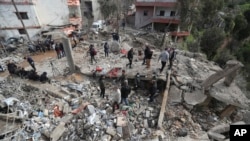 People gather on the rubble of a paramedic center that was destroyed by an Israeli airstrike in Hebbariye village, Lebanon, March 27, 2024. The airstrike on the center, which was linked to a Lebanese Sunni Muslim group, killed several of the group's members.